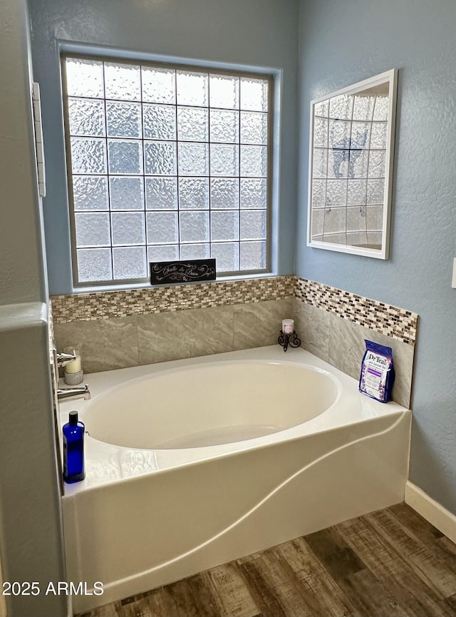 full bath with a bath, wood finished floors, and baseboards