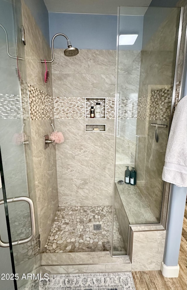bathroom with a shower stall and wood finished floors