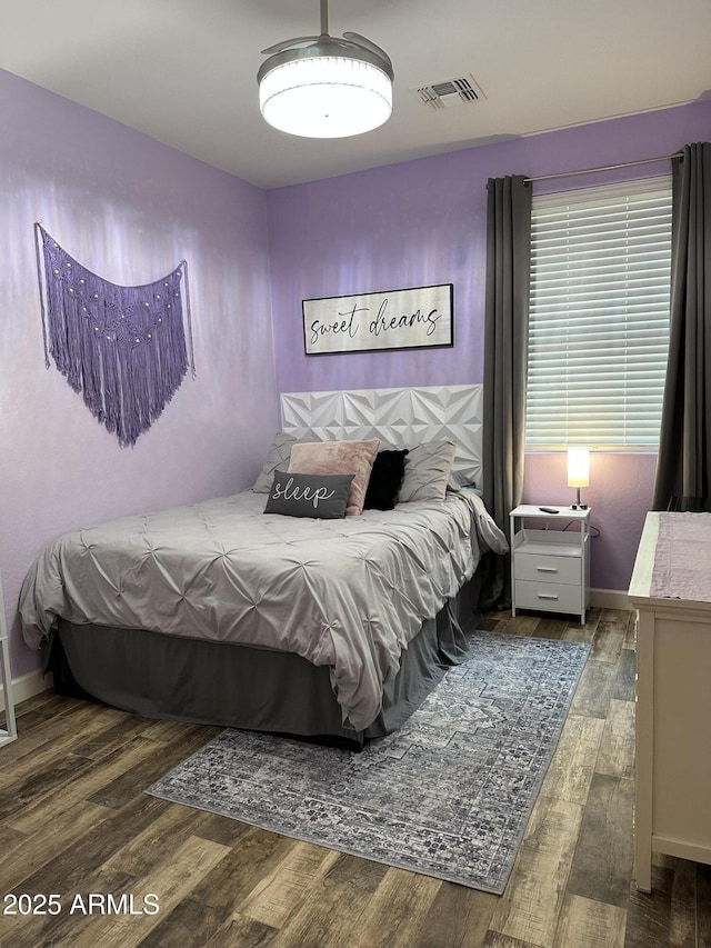 bedroom featuring wood finished floors, baseboards, and visible vents