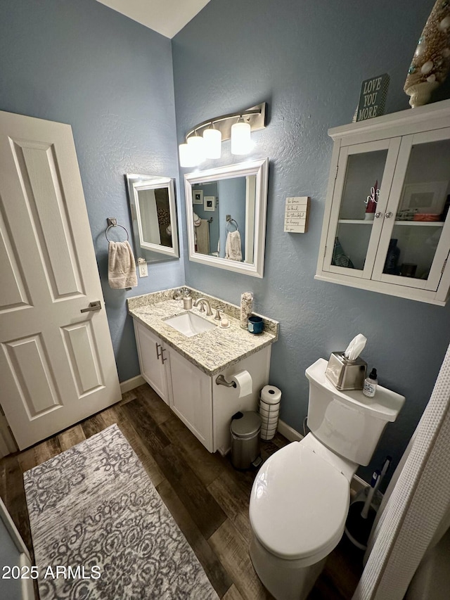 bathroom featuring toilet, wood finished floors, vanity, and baseboards