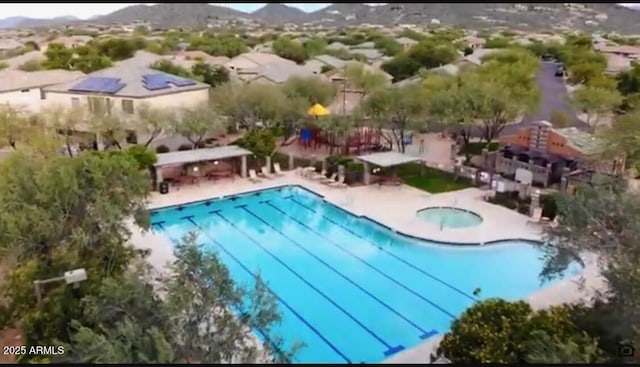 pool featuring a patio area, a community hot tub, and a mountain view