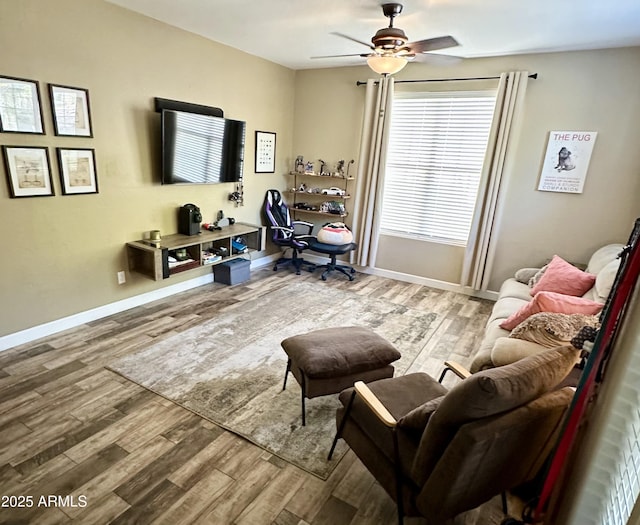living room featuring baseboards, a ceiling fan, and wood finished floors