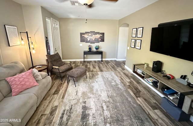 living area featuring visible vents, baseboards, arched walkways, ceiling fan, and wood finished floors