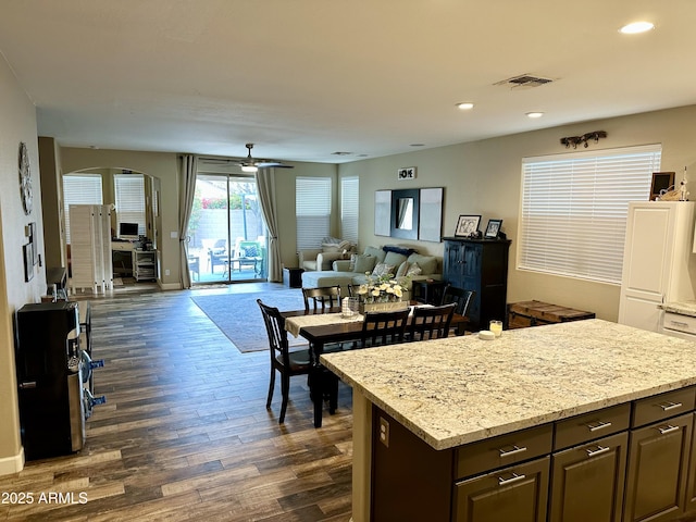 kitchen with visible vents, a center island, arched walkways, dark wood finished floors, and recessed lighting