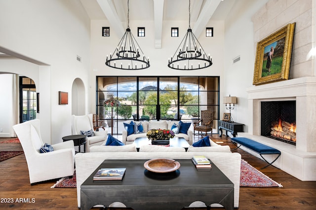 living room with a high ceiling, a tiled fireplace, beamed ceiling, and dark hardwood / wood-style flooring