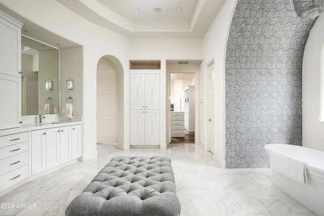 bathroom with vanity, a bathtub, and a tray ceiling