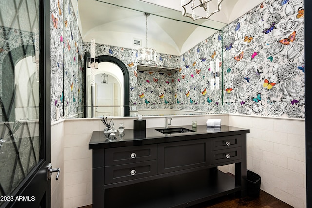 bathroom featuring vanity, vaulted ceiling, an inviting chandelier, tile walls, and hardwood / wood-style floors