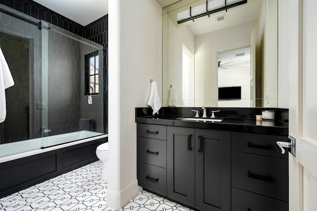 full bathroom with vanity, tile patterned flooring, ceiling fan, bath / shower combo with glass door, and toilet