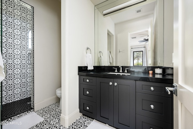 bathroom featuring ceiling fan, a shower, vanity, and toilet