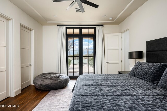 bedroom with dark hardwood / wood-style flooring, ceiling fan, and french doors