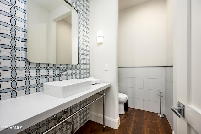 bathroom with hardwood / wood-style floors, tile walls, toilet, and vanity