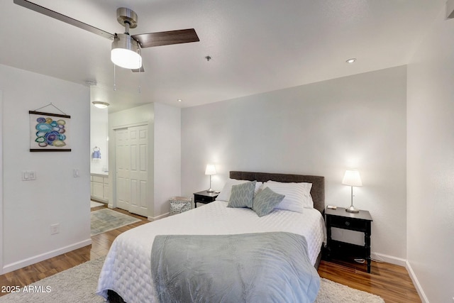 bedroom with ceiling fan, ensuite bathroom, wood finished floors, and baseboards