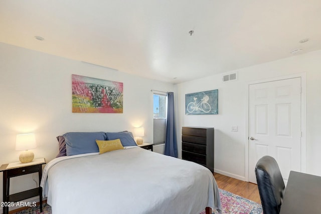 bedroom with light wood-style floors, visible vents, and baseboards