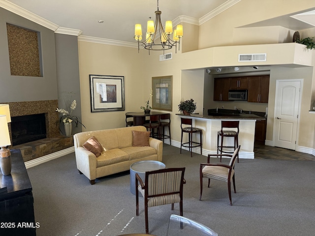 living area featuring a fireplace with raised hearth, ornamental molding, visible vents, and baseboards