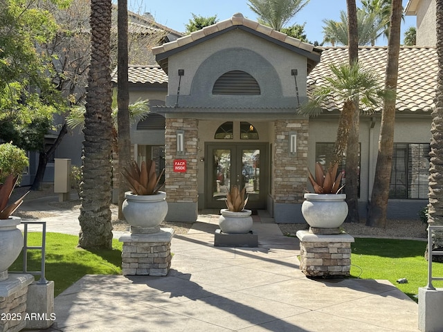 exterior space featuring a tiled roof, french doors, and stucco siding