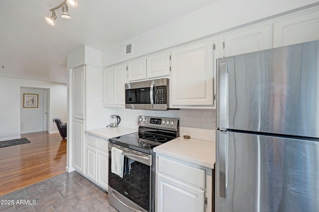 kitchen with stainless steel appliances, visible vents, light countertops, backsplash, and white cabinets