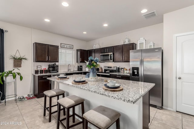 kitchen with a kitchen island, a kitchen bar, dark brown cabinetry, and stainless steel appliances