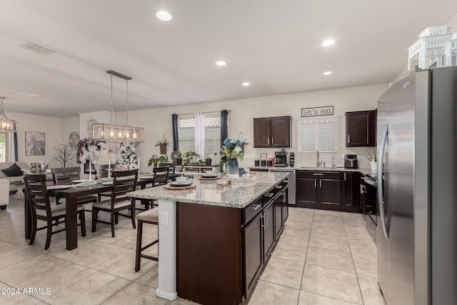 kitchen featuring pendant lighting, a breakfast bar, a center island, dark brown cabinetry, and stainless steel appliances