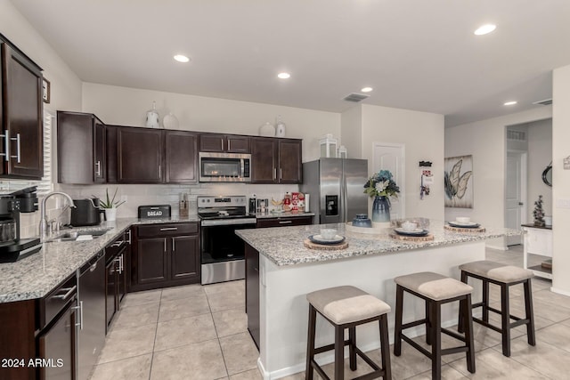 kitchen featuring a breakfast bar, a center island, sink, appliances with stainless steel finishes, and tasteful backsplash