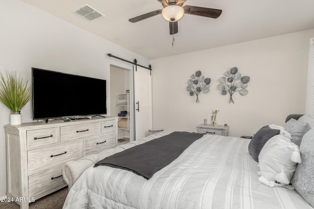 bedroom featuring ceiling fan and a barn door