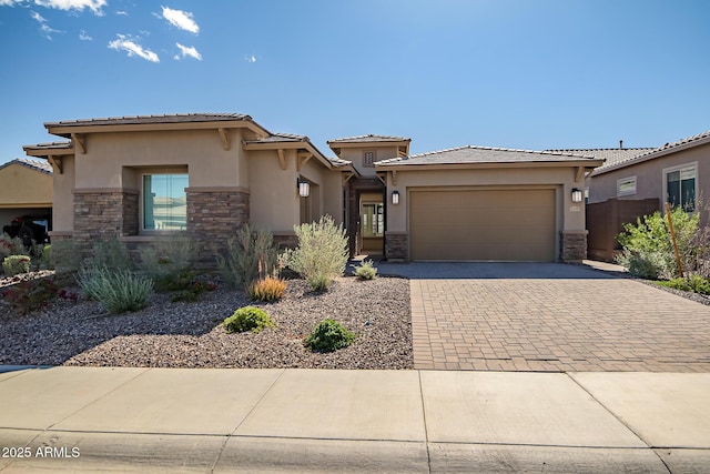 prairie-style home with stone siding, decorative driveway, and stucco siding