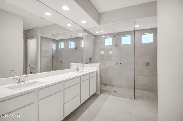 bathroom with a walk in shower, double vanity, a sink, and recessed lighting