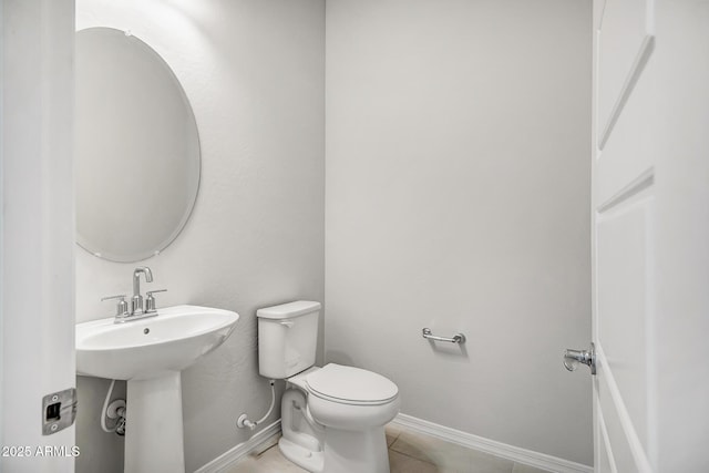 bathroom with toilet, tile patterned flooring, baseboards, and a sink