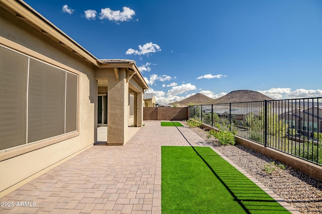 view of yard with a patio area, a fenced backyard, and a mountain view