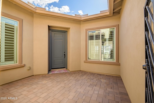 view of exterior entry with a patio area and stucco siding