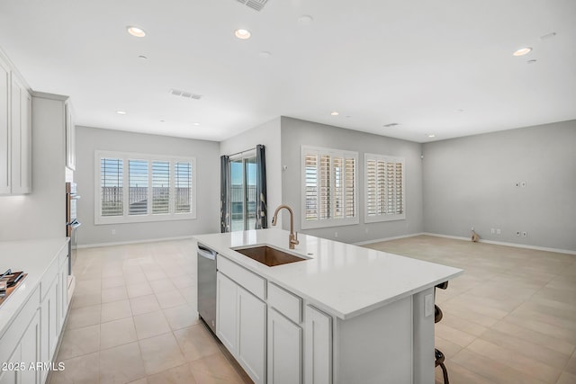 kitchen featuring a center island with sink, visible vents, open floor plan, stainless steel appliances, and a sink