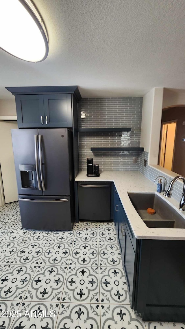 kitchen featuring blue cabinetry, sink, stainless steel appliances, backsplash, and a textured ceiling