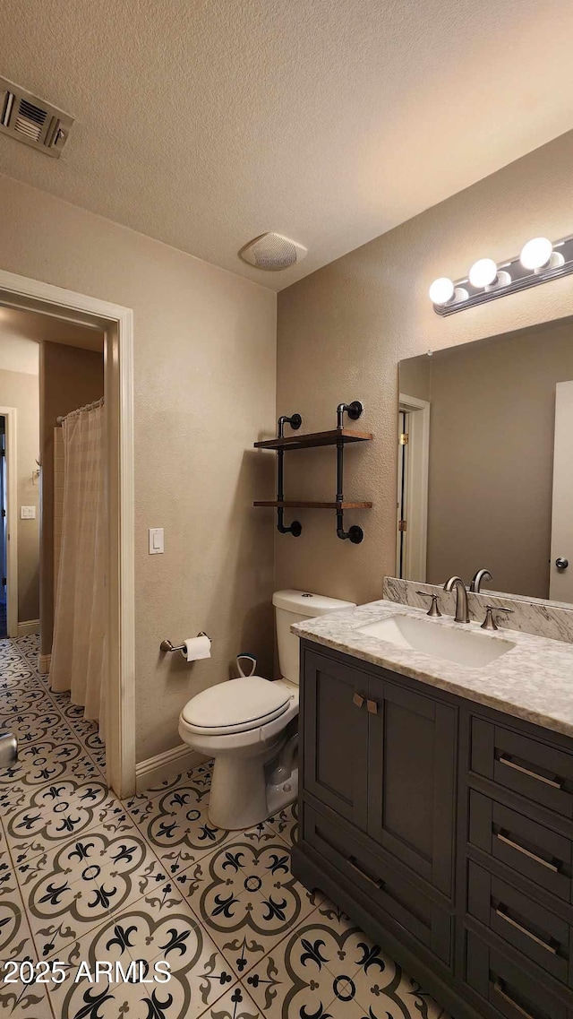 bathroom featuring vanity, a textured ceiling, tile patterned floors, and toilet