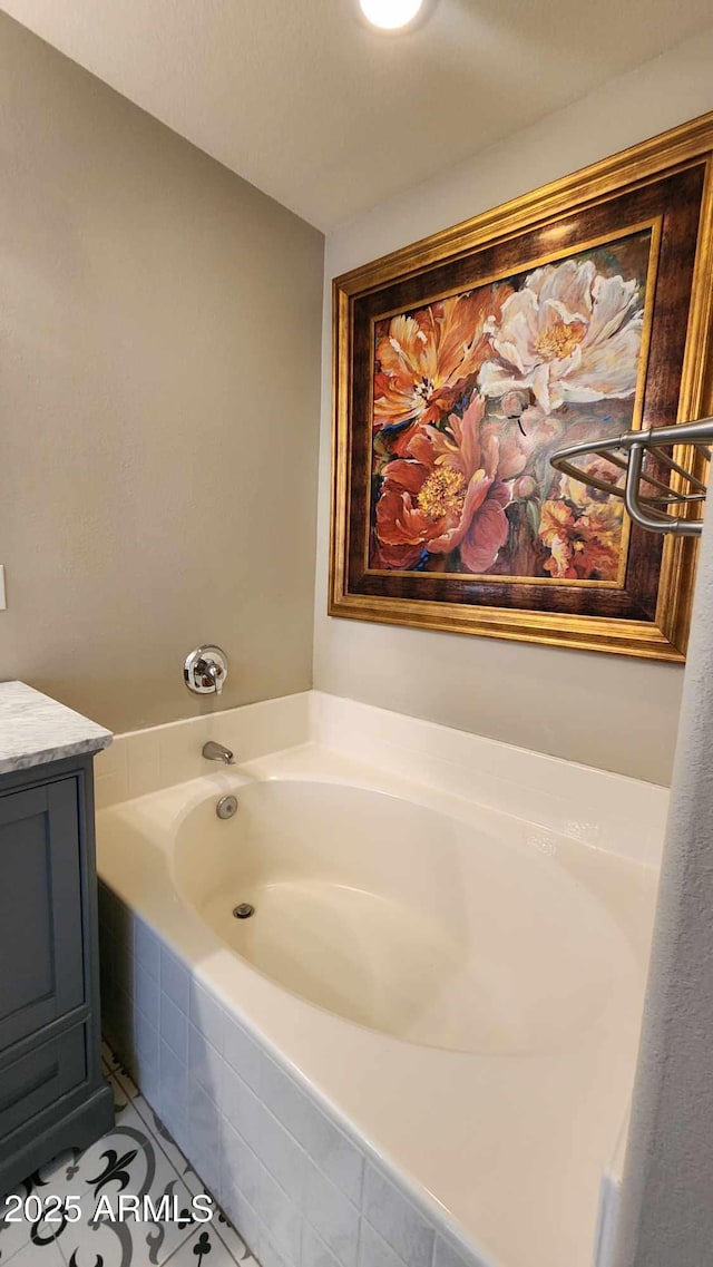 bathroom featuring tile patterned flooring, vanity, and tiled bath