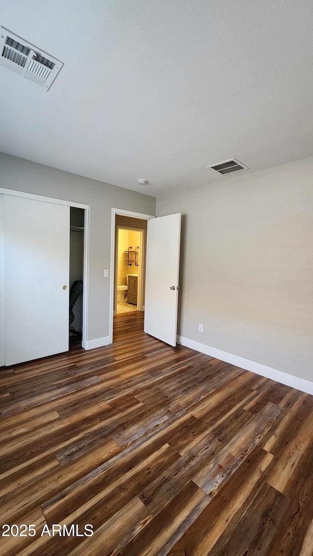 unfurnished bedroom featuring dark hardwood / wood-style floors and a closet