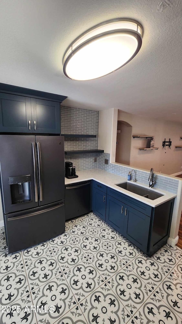 kitchen with sink, blue cabinetry, dishwasher, stainless steel fridge with ice dispenser, and light tile patterned flooring