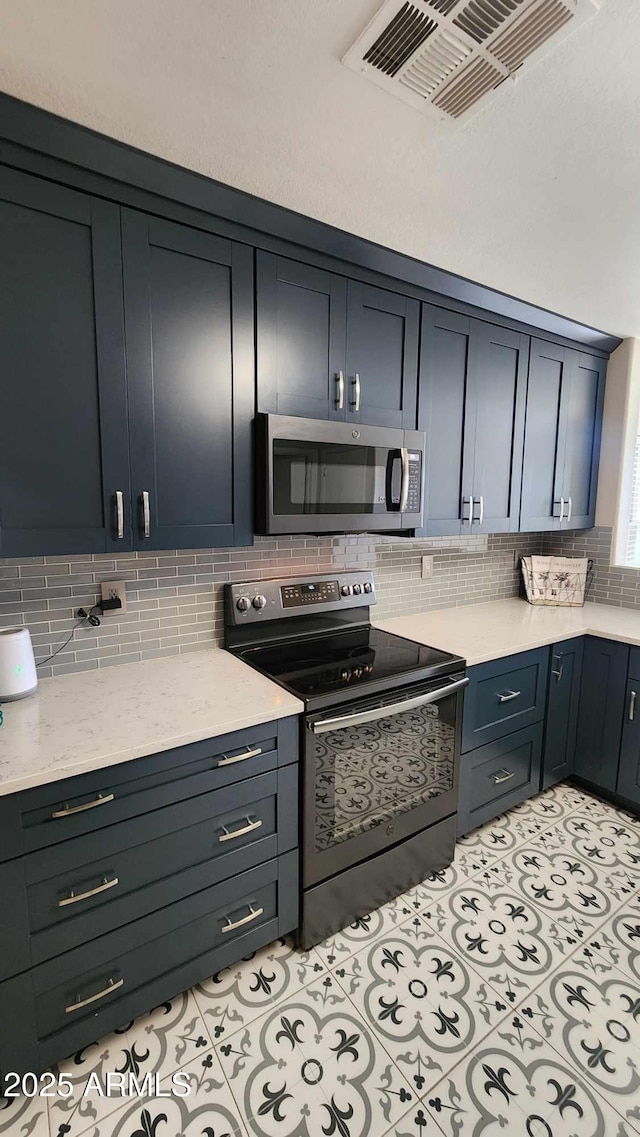 kitchen with decorative backsplash, light tile patterned floors, and stainless steel appliances