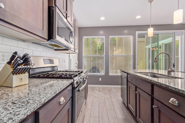 kitchen featuring light stone countertops, sink, stainless steel appliances, and plenty of natural light