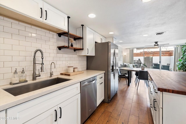 kitchen with dishwasher, backsplash, sink, ceiling fan, and white cabinetry