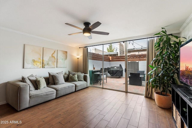 living room featuring hardwood / wood-style floors, ceiling fan, expansive windows, and crown molding