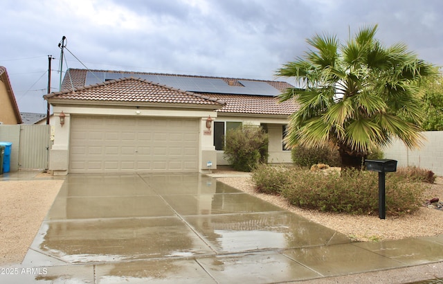 view of front facade featuring a garage, driveway, a tiled roof, roof mounted solar panels, and stucco siding