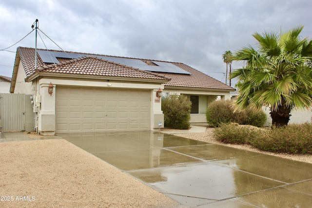 mediterranean / spanish home featuring a garage, solar panels, driveway, a gate, and stucco siding