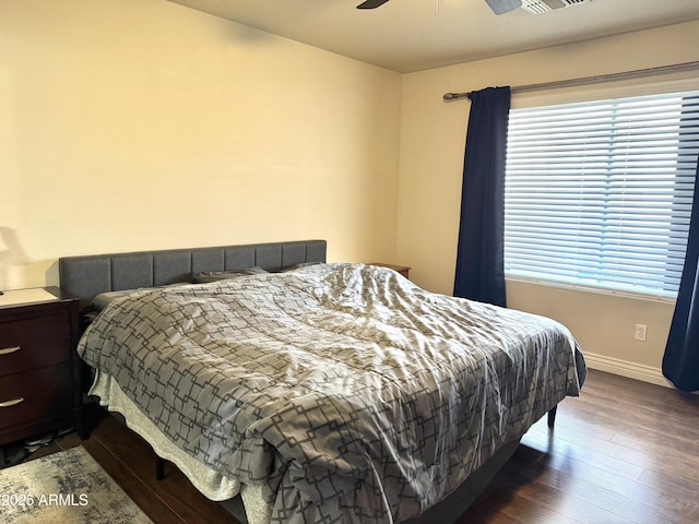 bedroom with ceiling fan, baseboards, and dark wood-type flooring