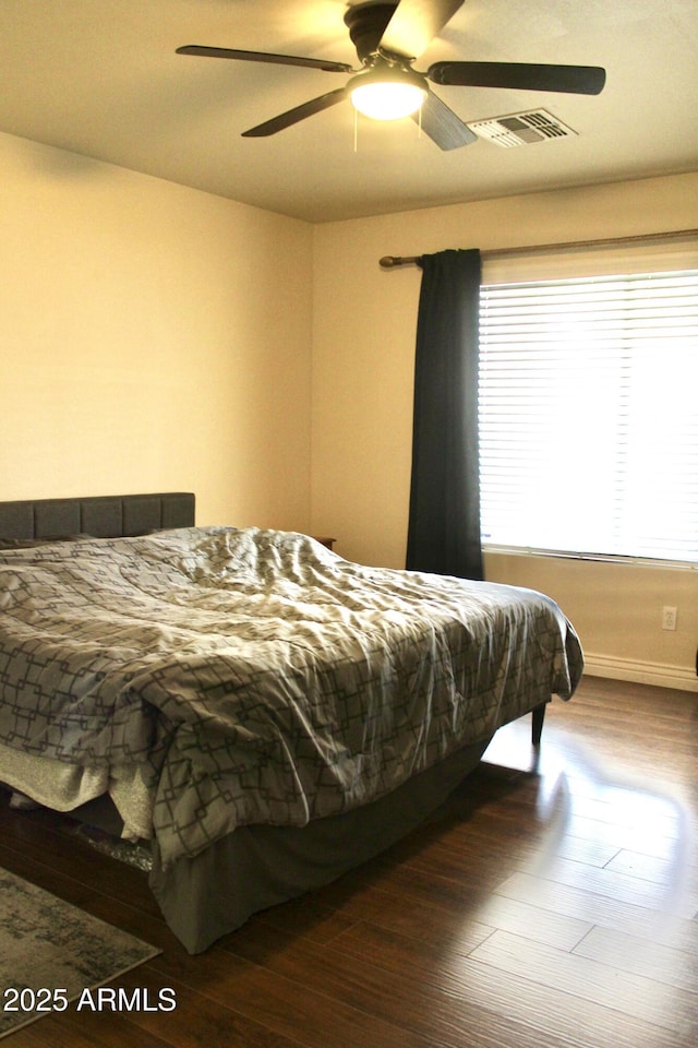 bedroom featuring wood finished floors, visible vents, and a ceiling fan