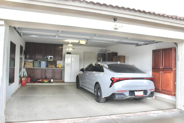 garage featuring white refrigerator with ice dispenser and electric water heater