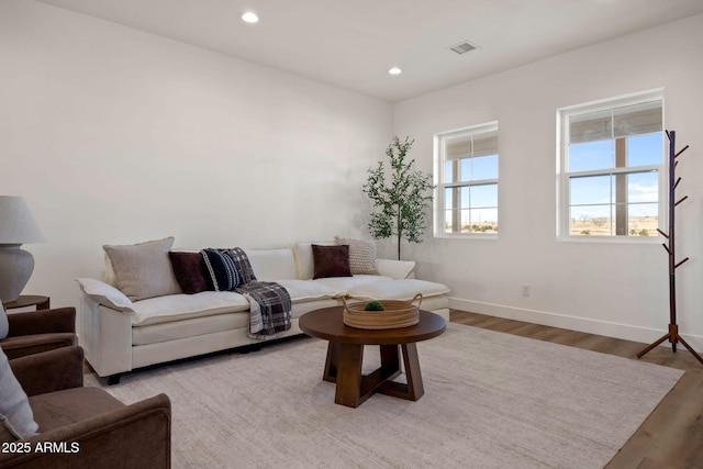 living area with baseboards, light wood finished floors, visible vents, and recessed lighting