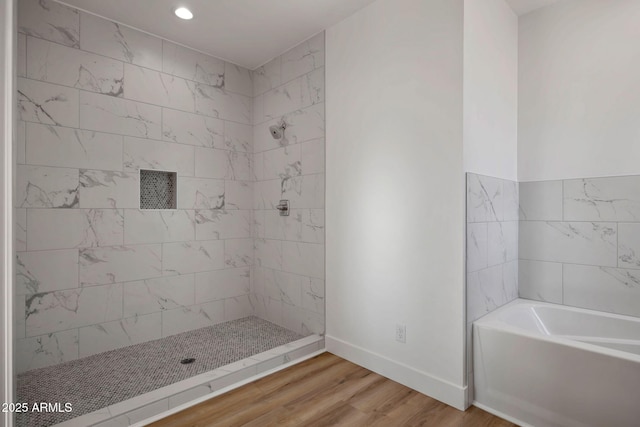 bathroom with a garden tub, a tile shower, wood finished floors, and baseboards