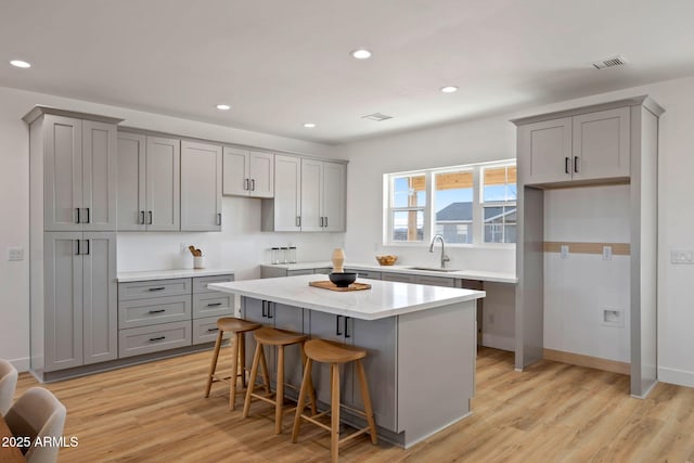 kitchen with a center island, gray cabinets, a sink, and a kitchen bar