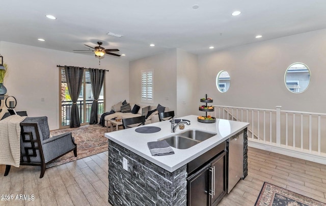 kitchen with ceiling fan, sink, dishwasher, and a kitchen island with sink