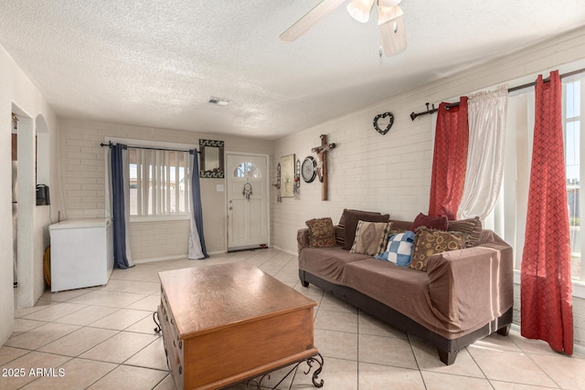 4403 N 56th Dr, Phoenix, AZ 85031 - living room featuring a textured ceiling, light tile patterned floors, a ceiling fan, and brick wall