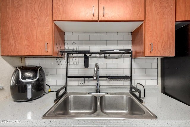 4403 N 56th Dr, Phoenix, AZ 85031 - kitchen featuring a sink, tasteful backsplash, brown cabinets, and light stone counters